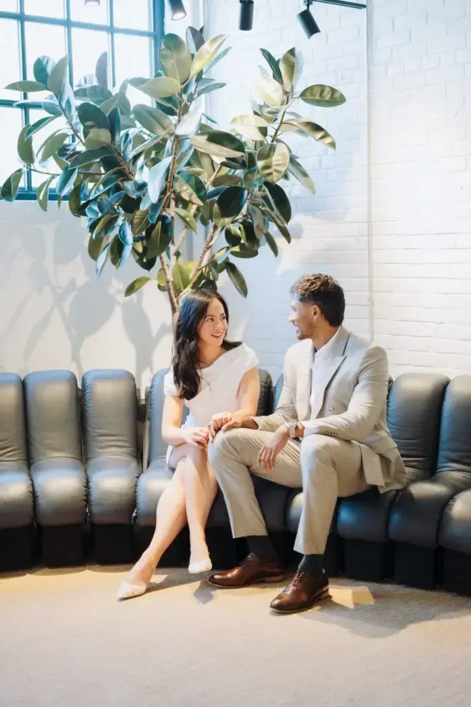 Neel and Grace holding hands on a sunlit sofa