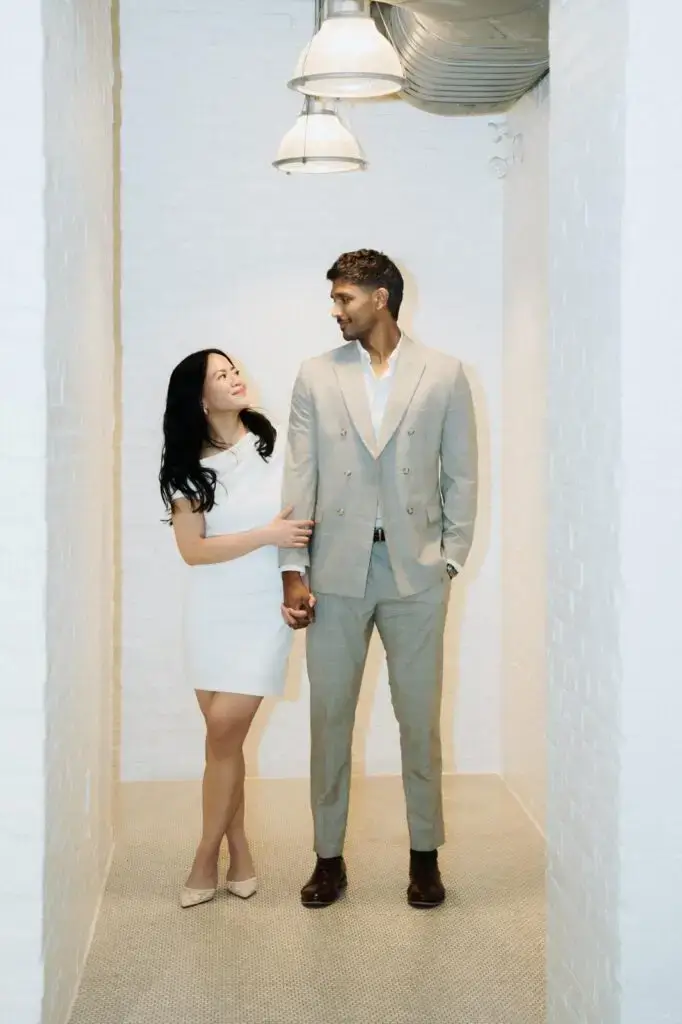 Neel and Grace holding hands in a sunlit hallway