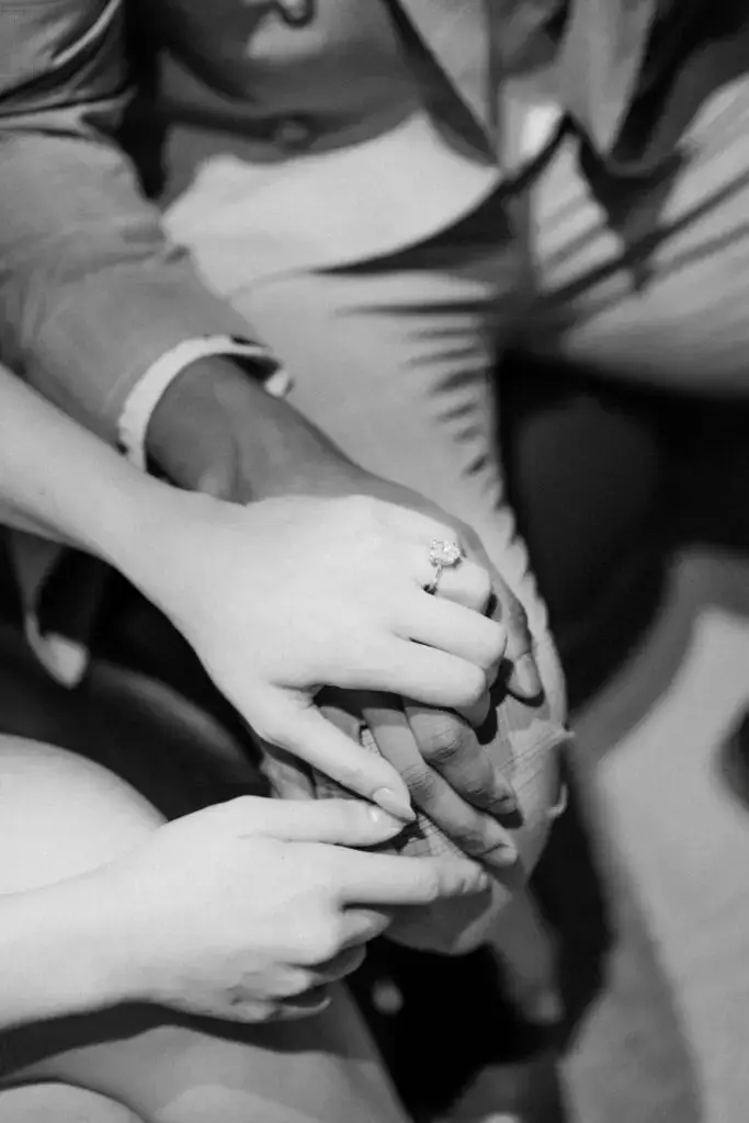 A close-up of Neel and Grace holding hands, with Grace’s engagement ring